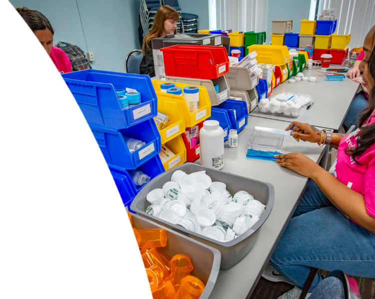 Healthcare workers organizing medications and supplies using colorful sorting bins and prescription bottles.